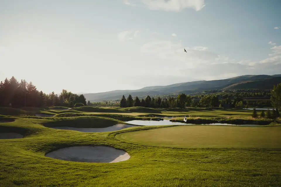 Golf green with bunkers and a pond in a Colorado mountain valley